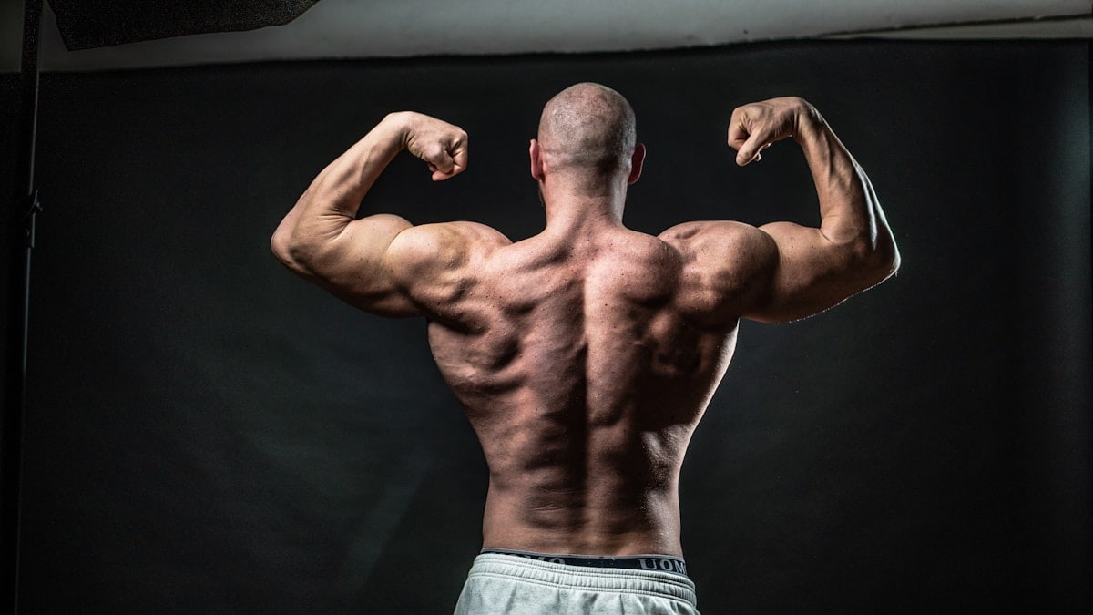 a man flexing his muscles in front of a black background